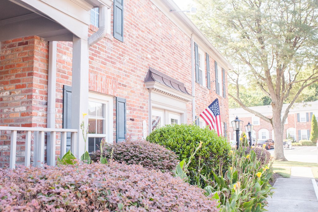the front porch of a brick building with an flag