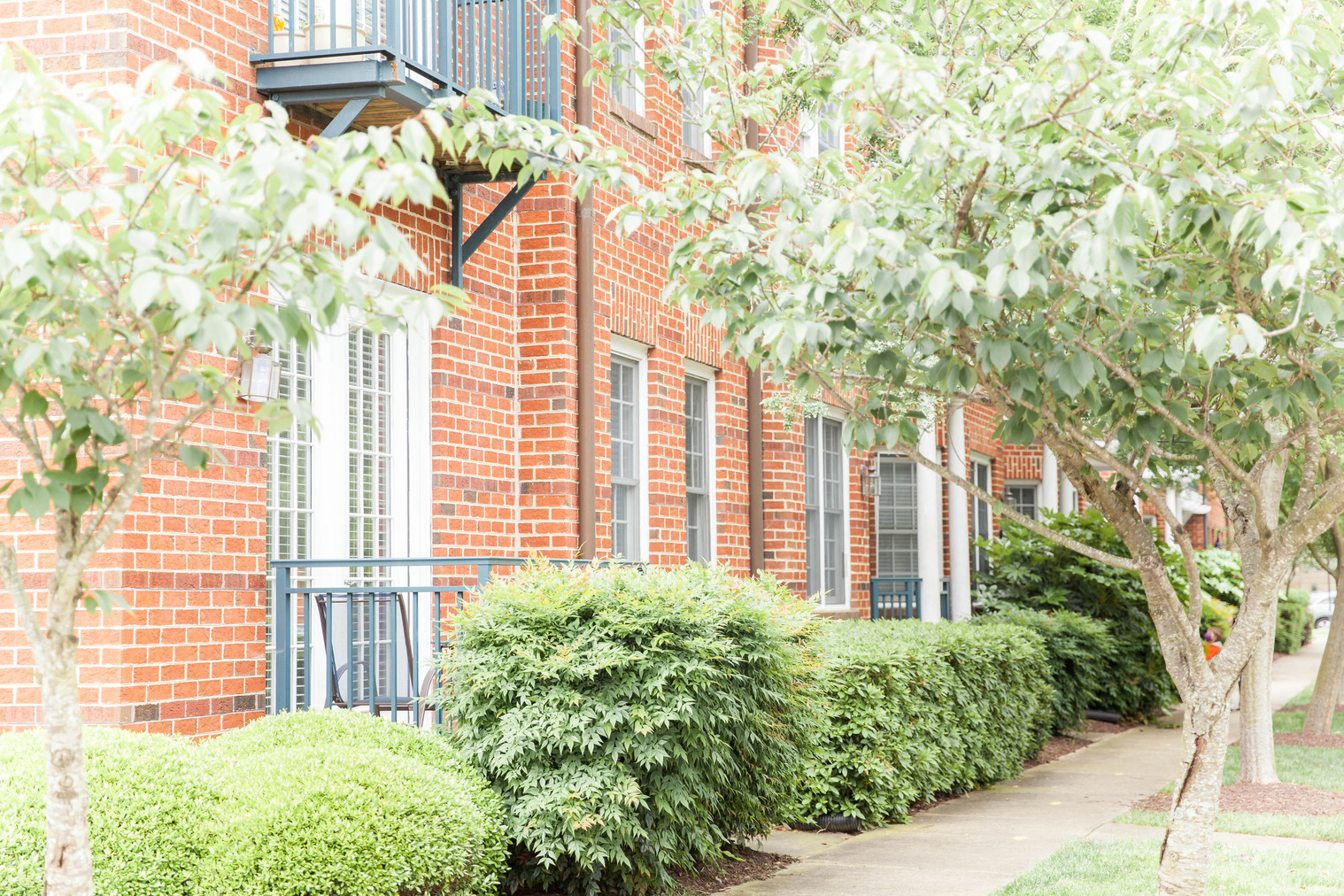 a brick building with trees and bushes in front of it