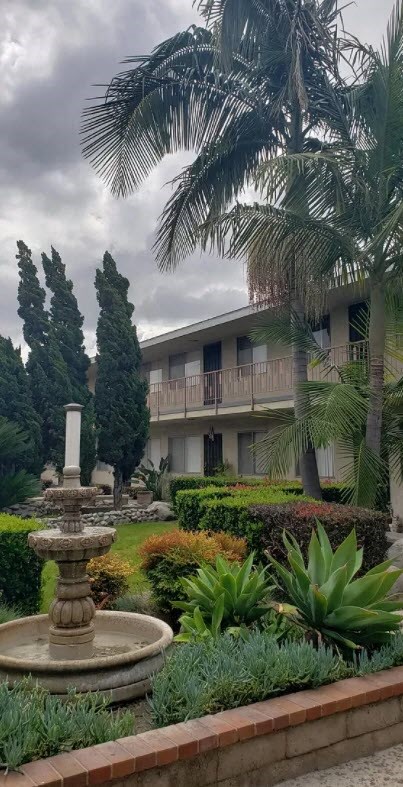 a fountain in a garden in front of a building