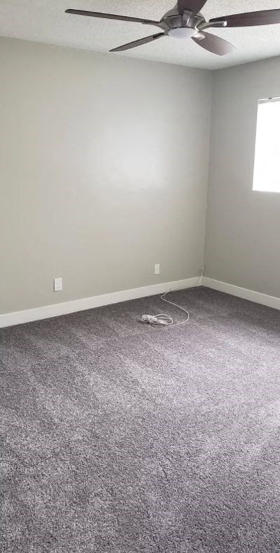 an empty room with a ceiling fan and carpet