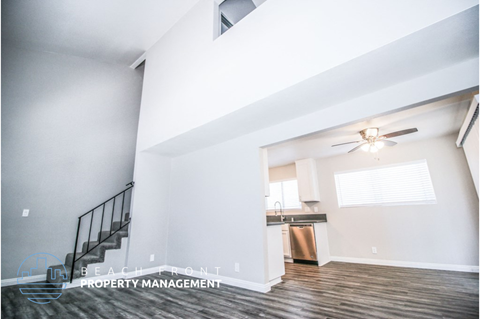 a living room with a ceiling fan and a staircase