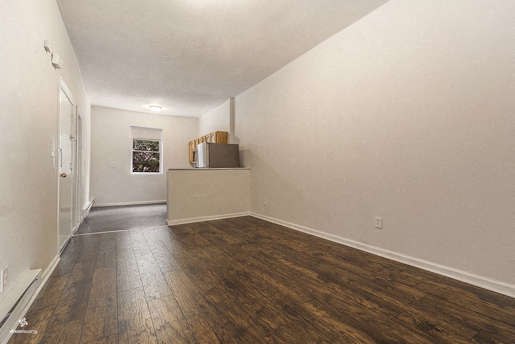 an empty living room with wood flooring and white walls