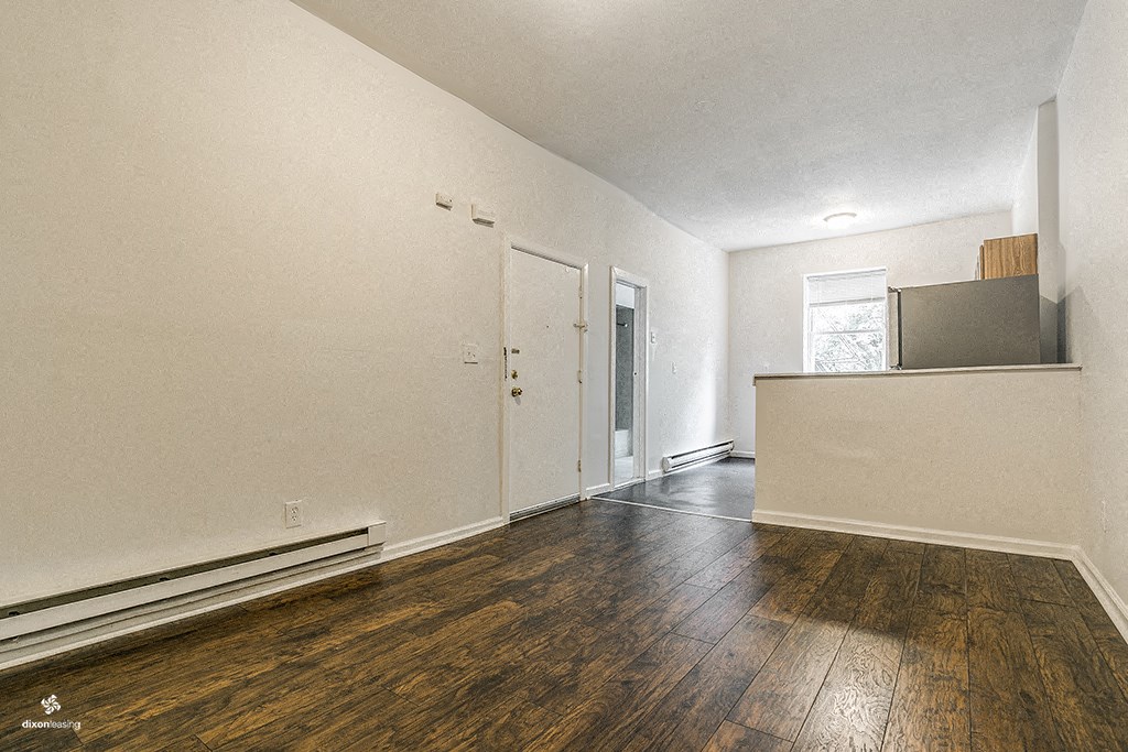 an empty living room with hard wood floors and white walls