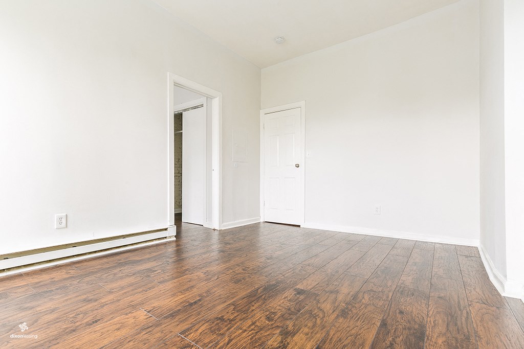 an empty room with wood floors and white walls
