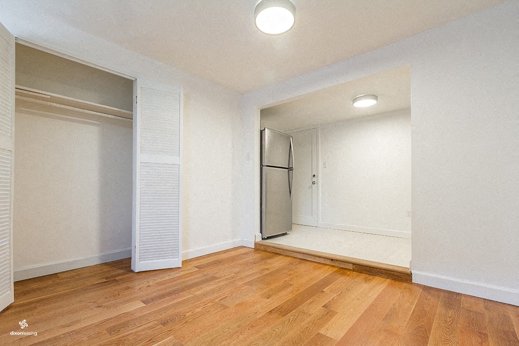 an empty room with a closet and a hard wood floor