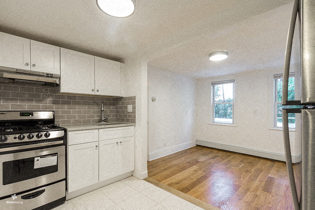 an empty kitchen with stainless steel appliances and white cabinets