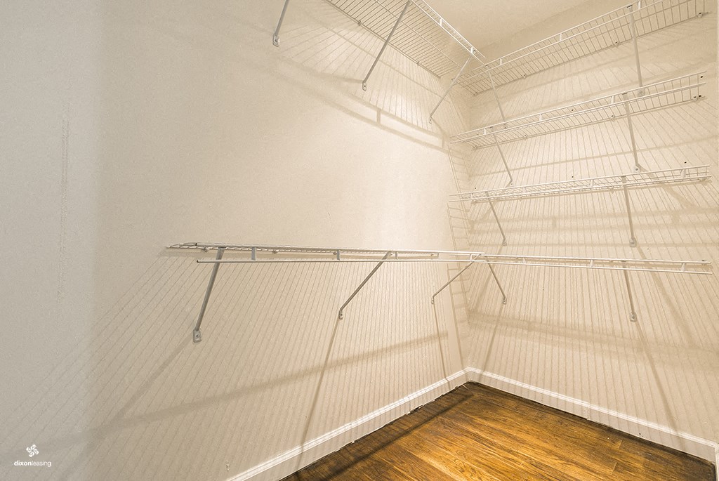 a walk in closet with empty shelves and a wood floor