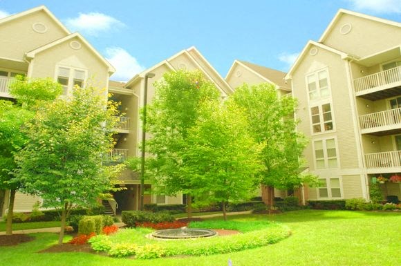 an apartment building with a green yard and trees