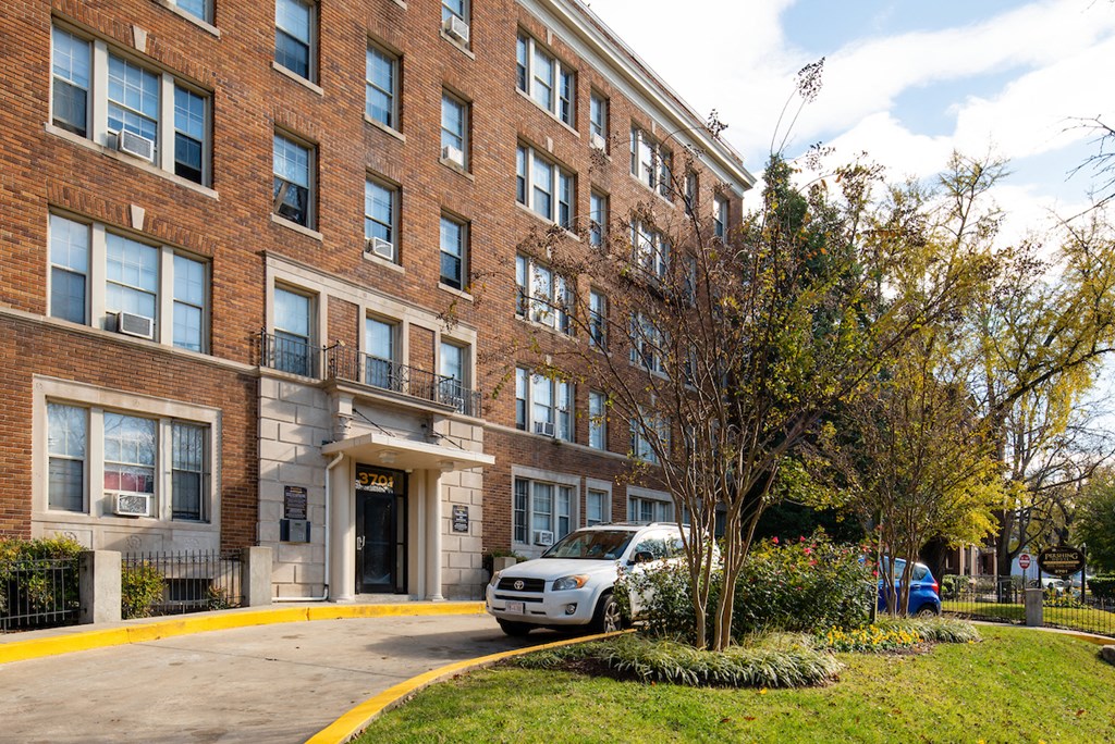 a large brick apartment building with a car parked outside