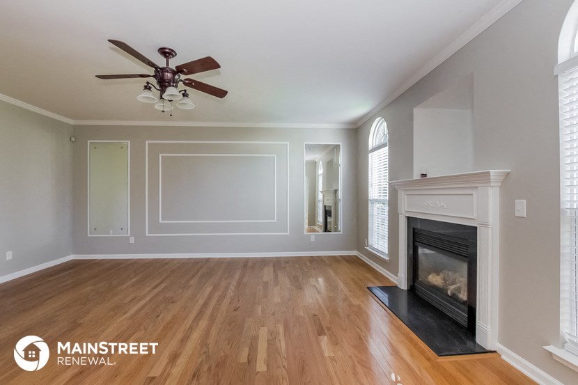 a living room with a fireplace and a ceiling fan