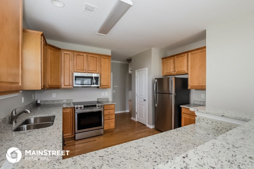 a kitchen with wooden cabinets and granite counter tops and a stainless steel refrigerator