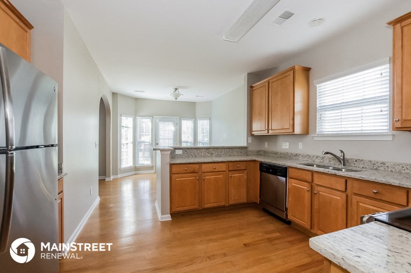 a kitchen with wooden cabinets and granite counter tops and a stainless steel refrigerator
