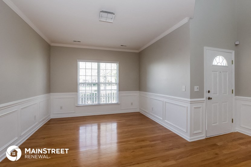 the living room of a home with white walls and wood floors