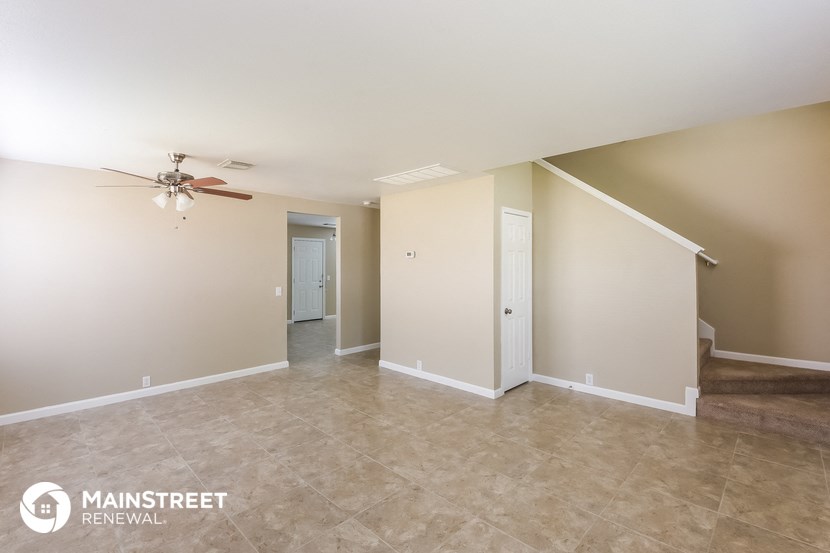 the spacious living room with tile flooring and a ceiling fan