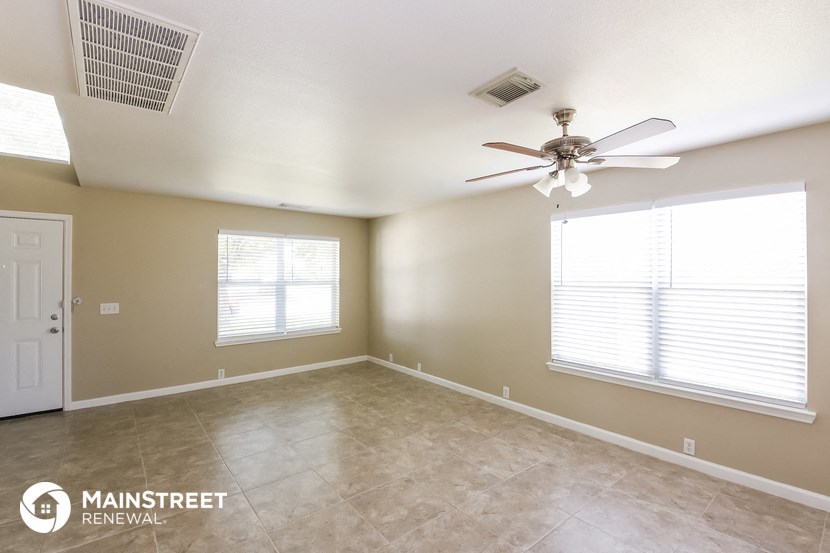 an empty room with a ceiling fan and two windows