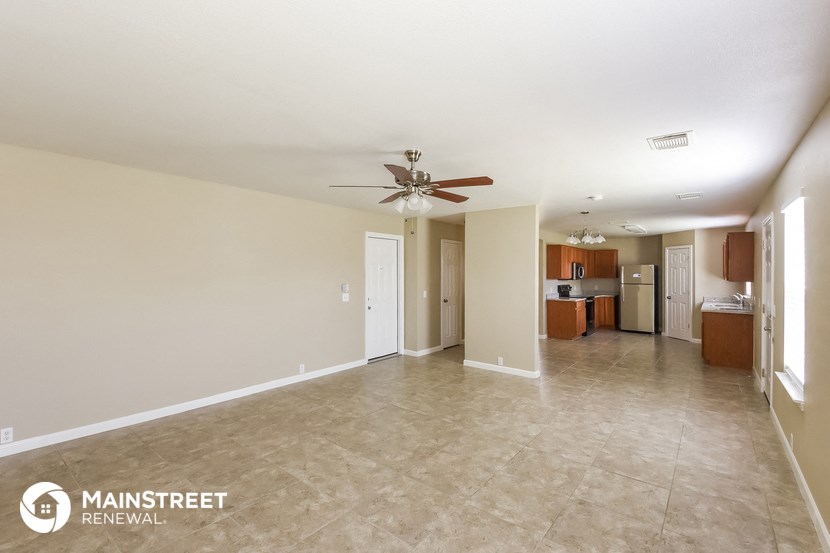 a spacious living room with tile flooring and a ceiling fan