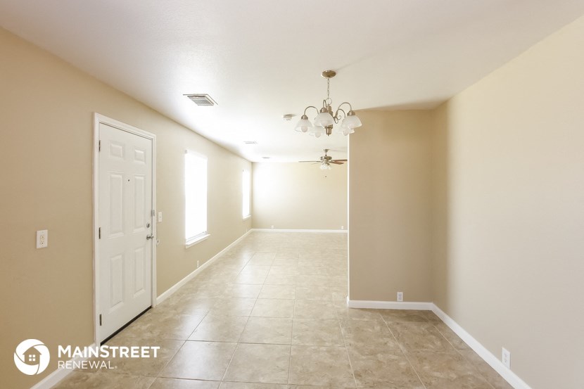 the living room and dining room with a white door and tiled floor