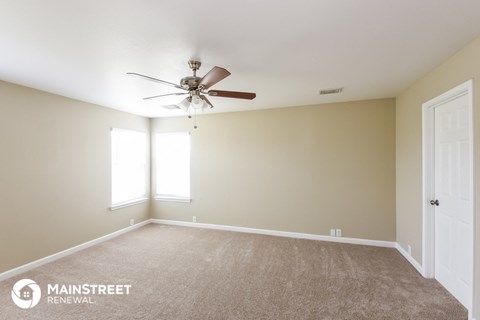 a living room with a ceiling fan and a carpet
