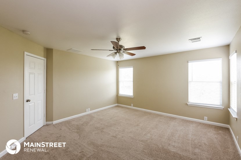 a living room with carpet and a ceiling fan
