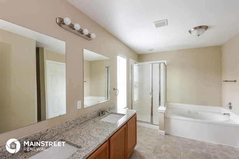 the master bathroom has a large vanity mirror and a tub and shower