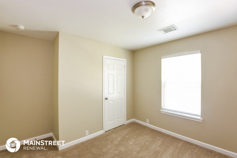 an empty room with a white door and a window