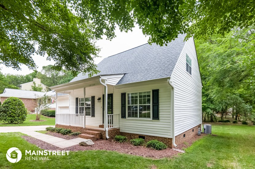 a small white house with a front porch and a yard with trees