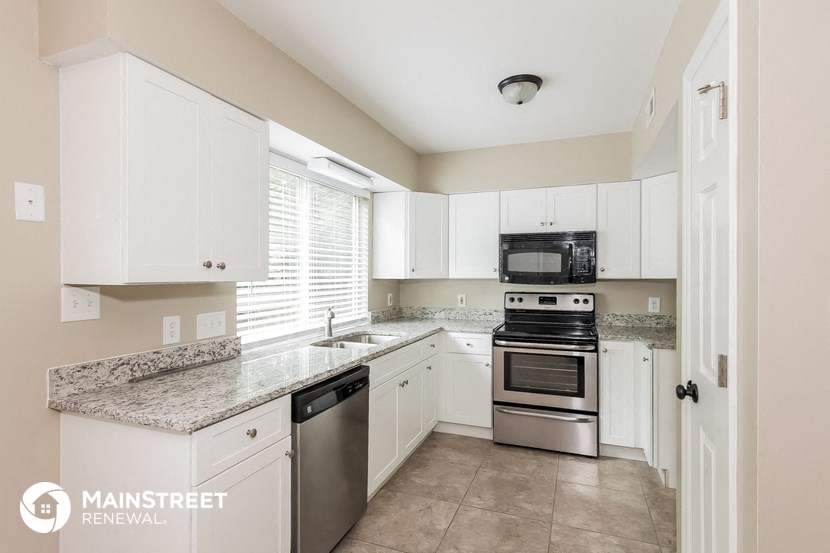 a kitchen with white cabinets and granite counter tops and stainless steel appliances