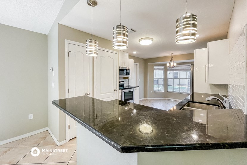 a kitchen with white cabinets and a black counter top