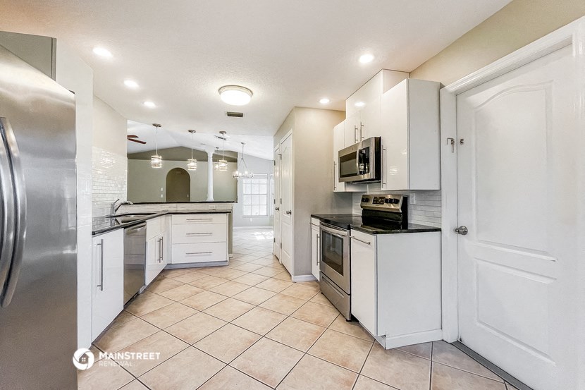 a large kitchen with white cabinets and stainless steel appliances