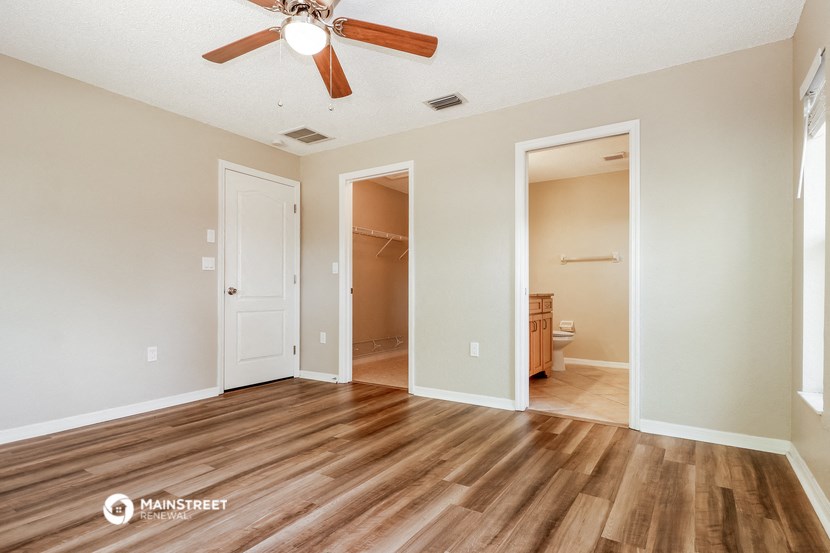 an empty living room with wood flooring and a ceiling fan