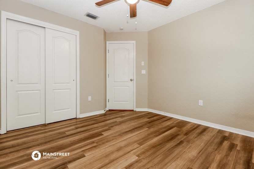 the spacious living room with wood flooring and a ceiling fan