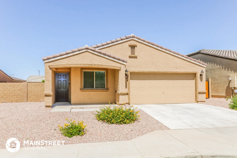 a tan house with a garage door and a driveway