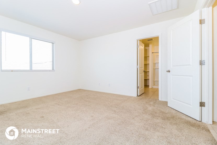 a bedroom with white walls and carpet and a door to a closet