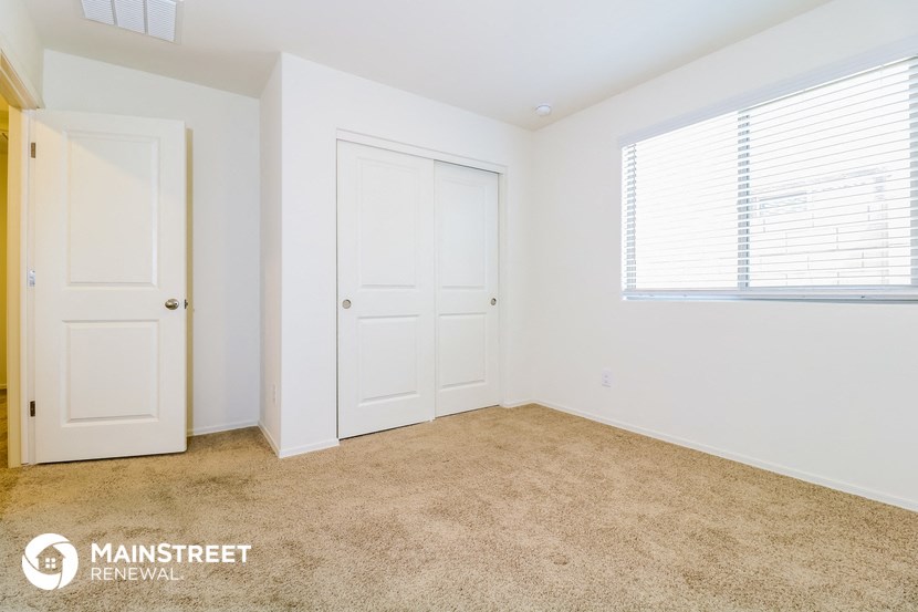 a bedroom with two doors and a window and a carpeted floor