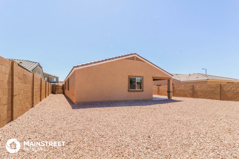 a small brown house with a gravel yard and a fence