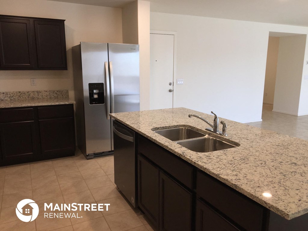 a kitchen with granite counter tops and a stainless steel refrigerator