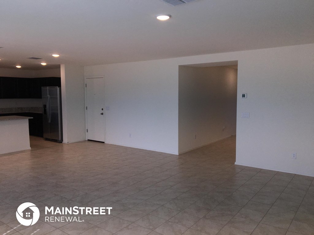 an empty living room with white walls and a tile floor
