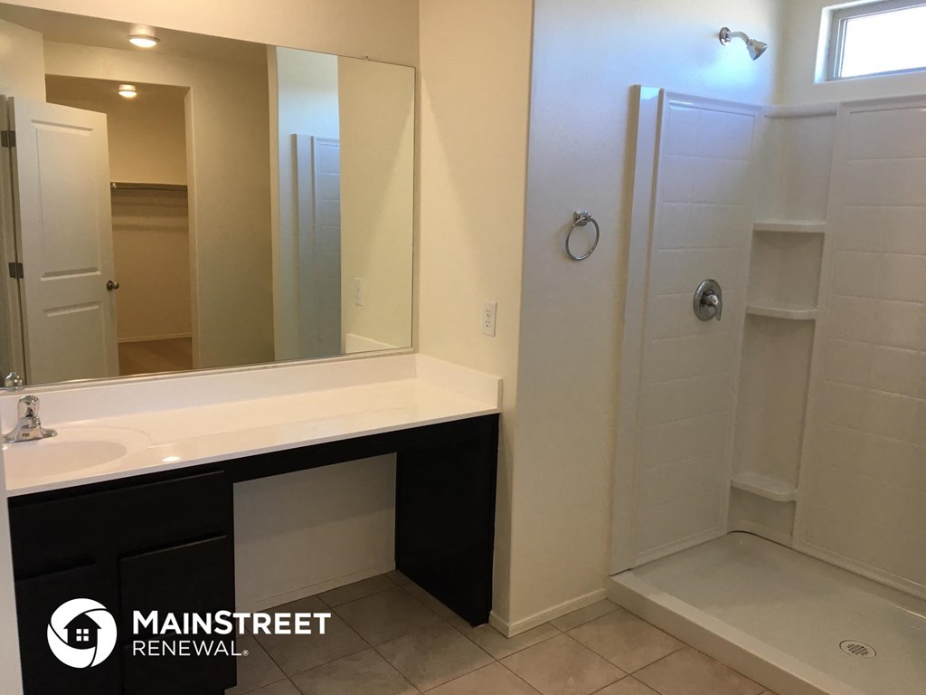 a bathroom with a sink and a shower and a mirror