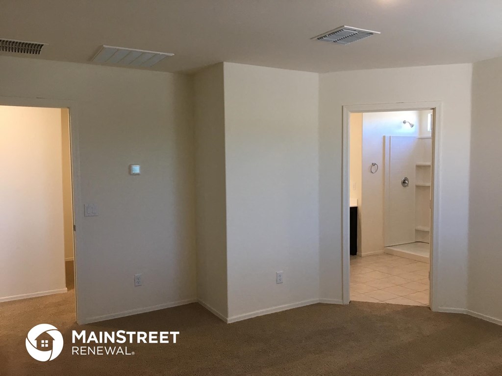 an empty living room with white walls and a door to a bathroom