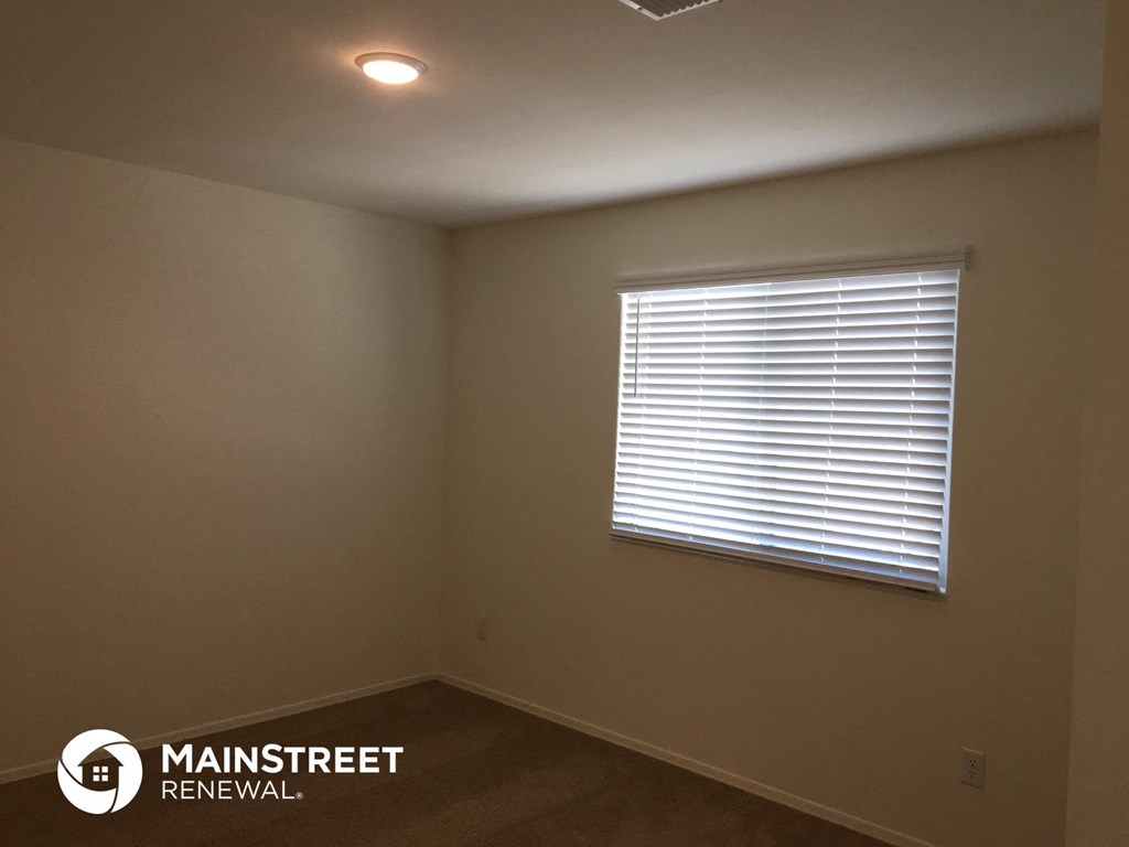 the bedroom of a house with a window and blinds