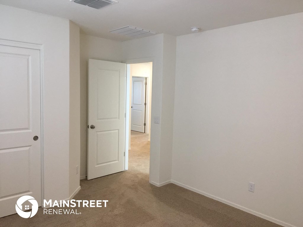a bedroom with white walls and a door to a hallway