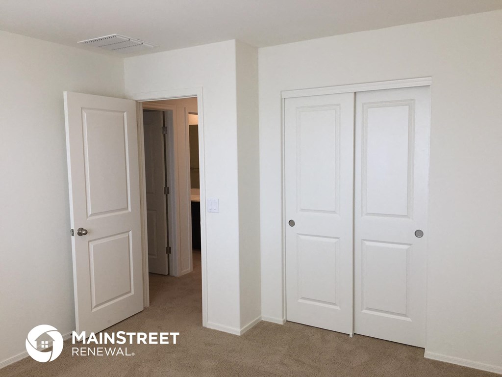 a bedroom with two white closets and a hallway with two doors