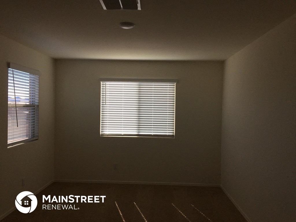 an empty room with two windows and a ceiling fan