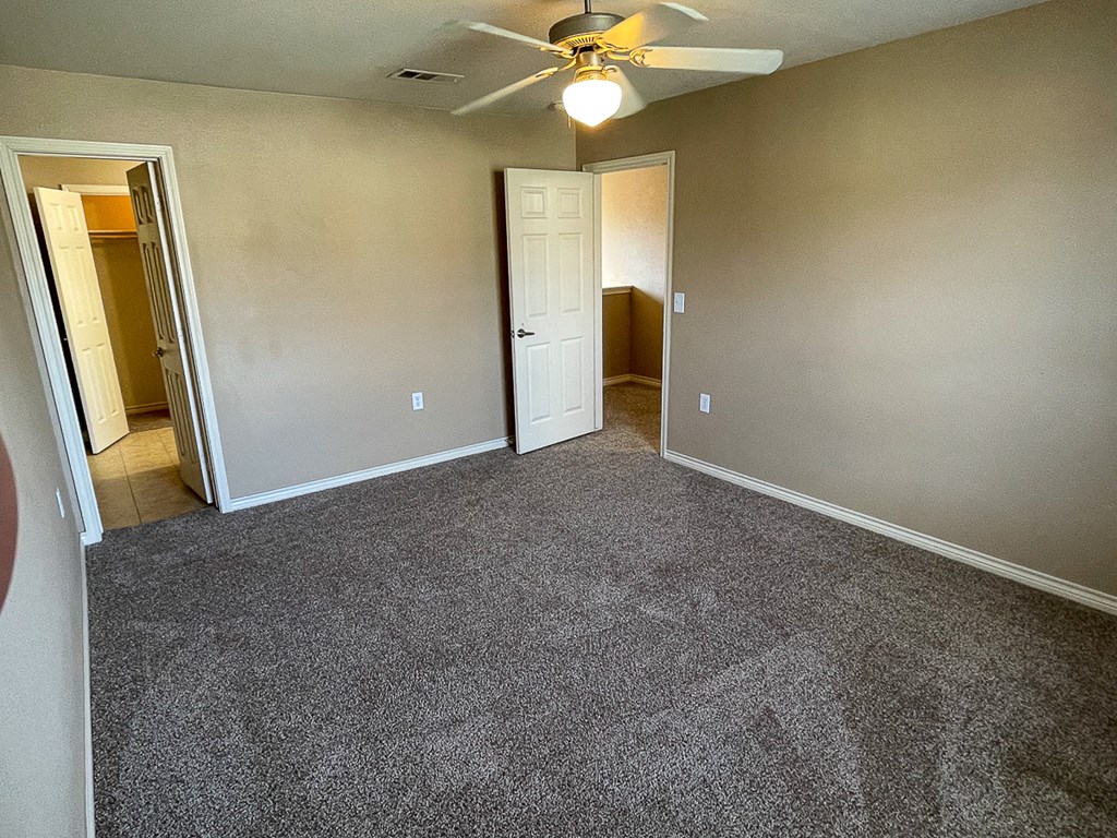 an empty living room with carpet and a ceiling fan