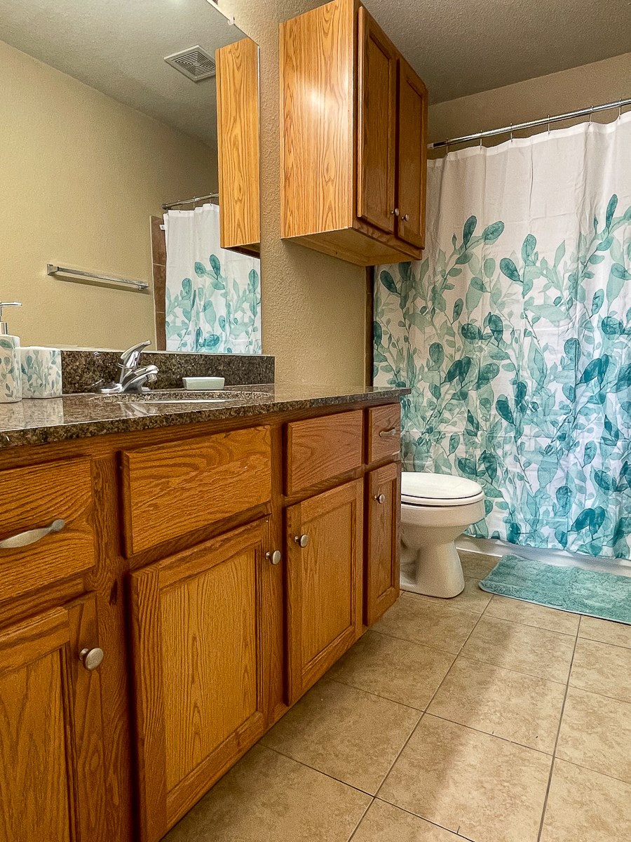 a bathroom with wooden cabinets and a toilet and a shower curtain