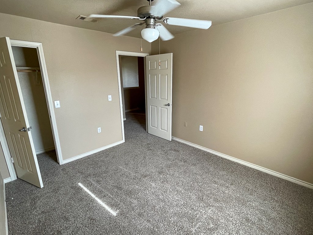 an empty room with a ceiling fan and a door to a closet