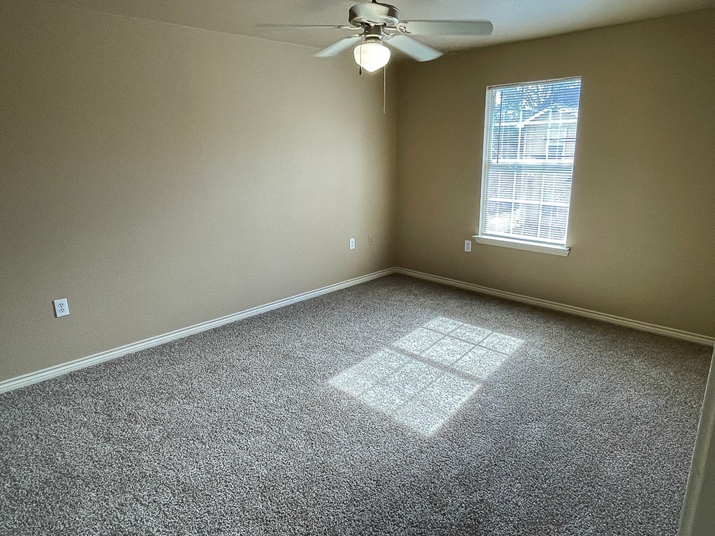 an empty room with a ceiling fan and a window
