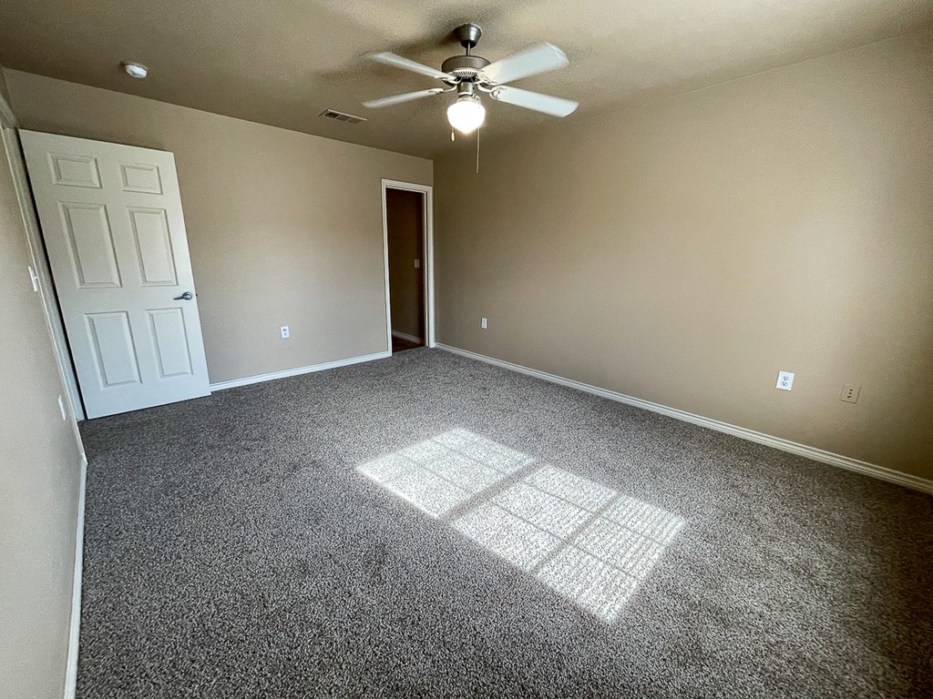 an empty living room with a ceiling fan
