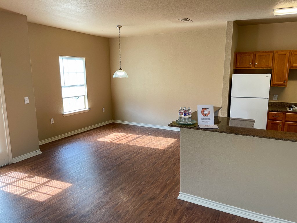 an empty kitchen and living room with wood floors