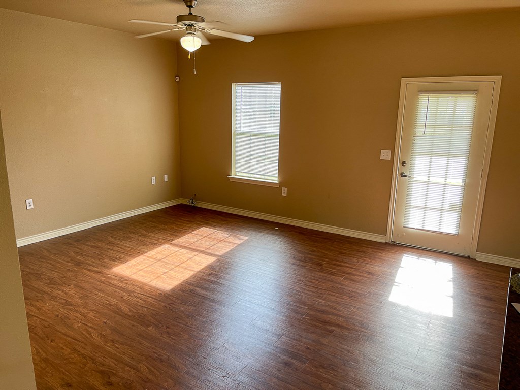 an empty living room with wooden floors and a ceiling fan